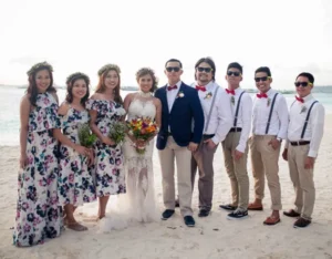 Bridal party in floral dresses and casual suits posing on the beach