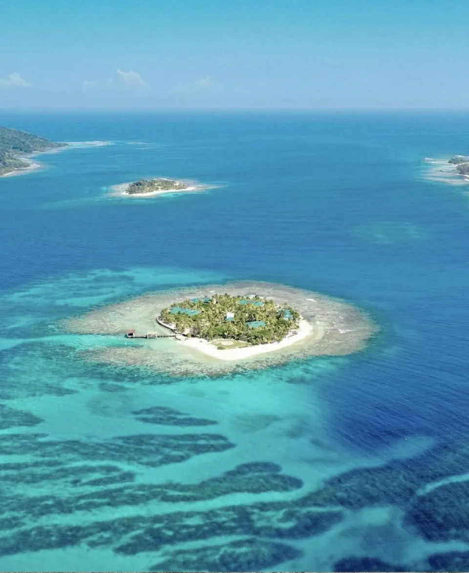 Aerial view of a small Caribbean cay surrounded by turquoise water and reefs