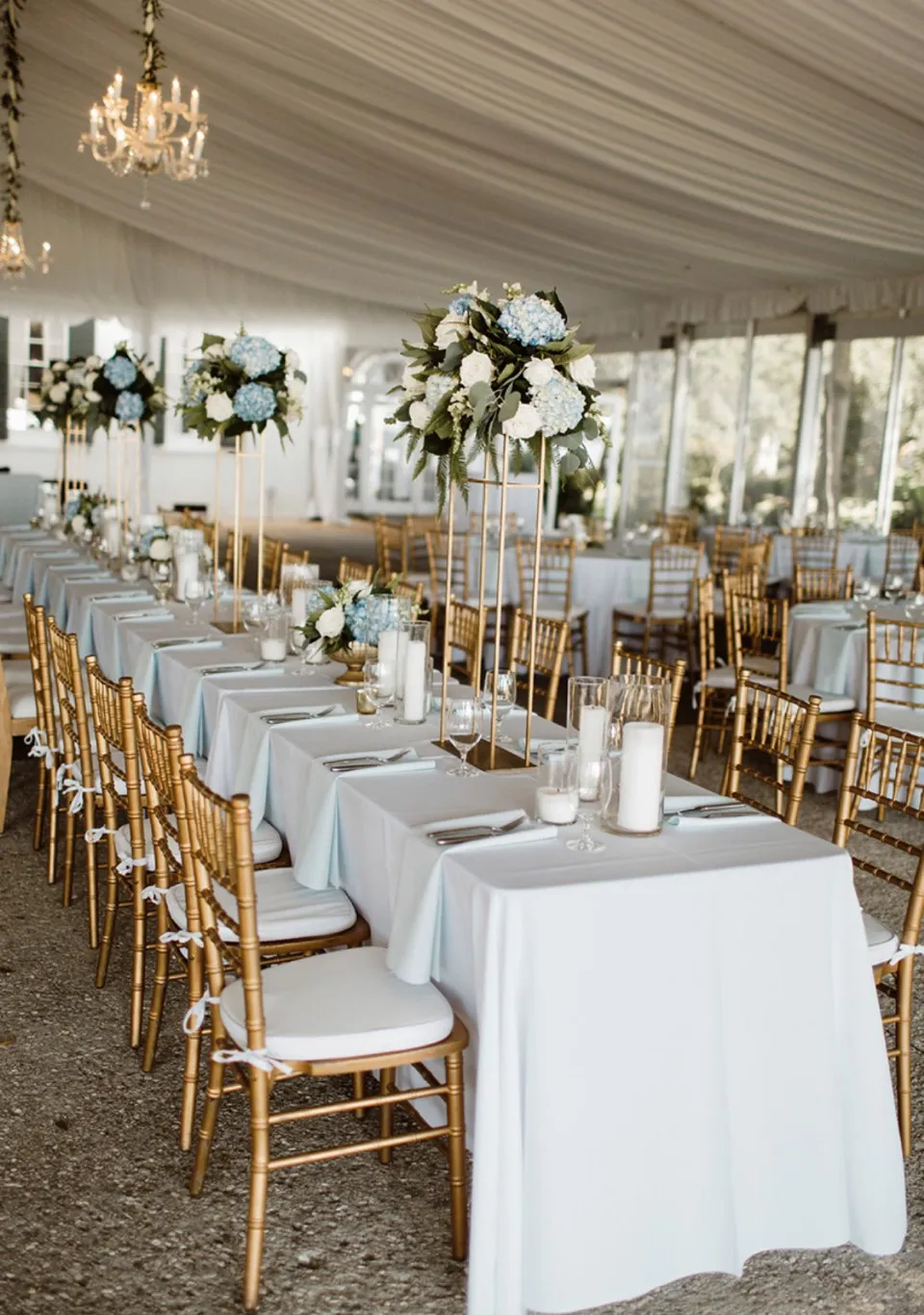 Elegant tent wedding reception with long tables, white linens and chandeliers