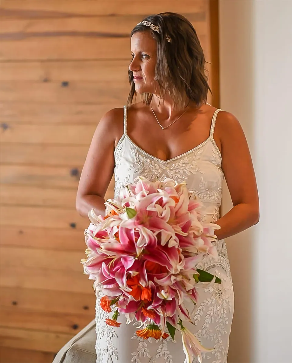 Bride holding a bouquet of pink lilies and tropical flowers