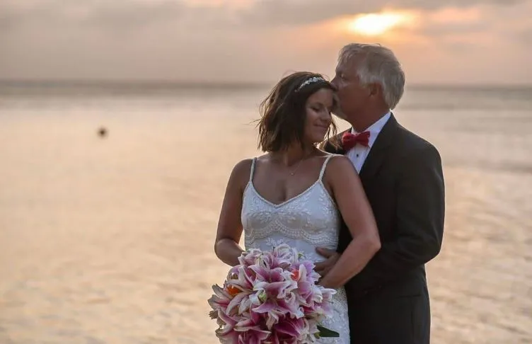 Groom kissing the bride's forehead at sunset on the beach in Roatán