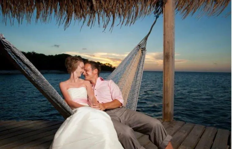 Bride and groom relaxing in a hammock on a dock at sunset