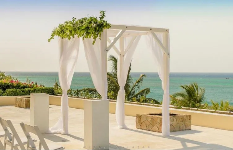 White draped wedding arch with greenery on an ocean-view terrace