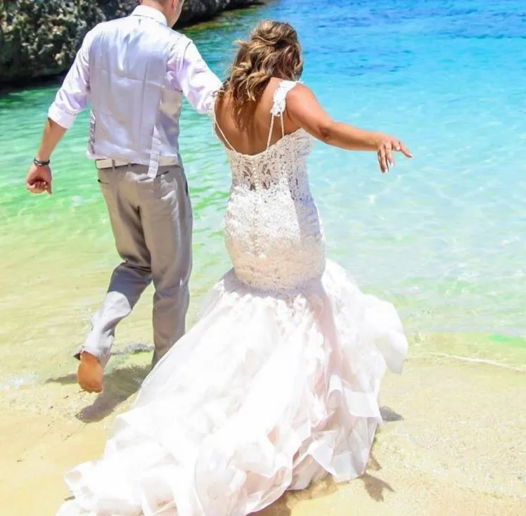Bride and groom walking into the turquoise Caribbean water after their beach wedding