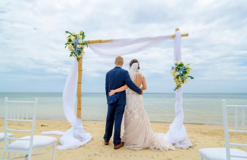 Beach wedding arch with white draping and flowers in Roatán