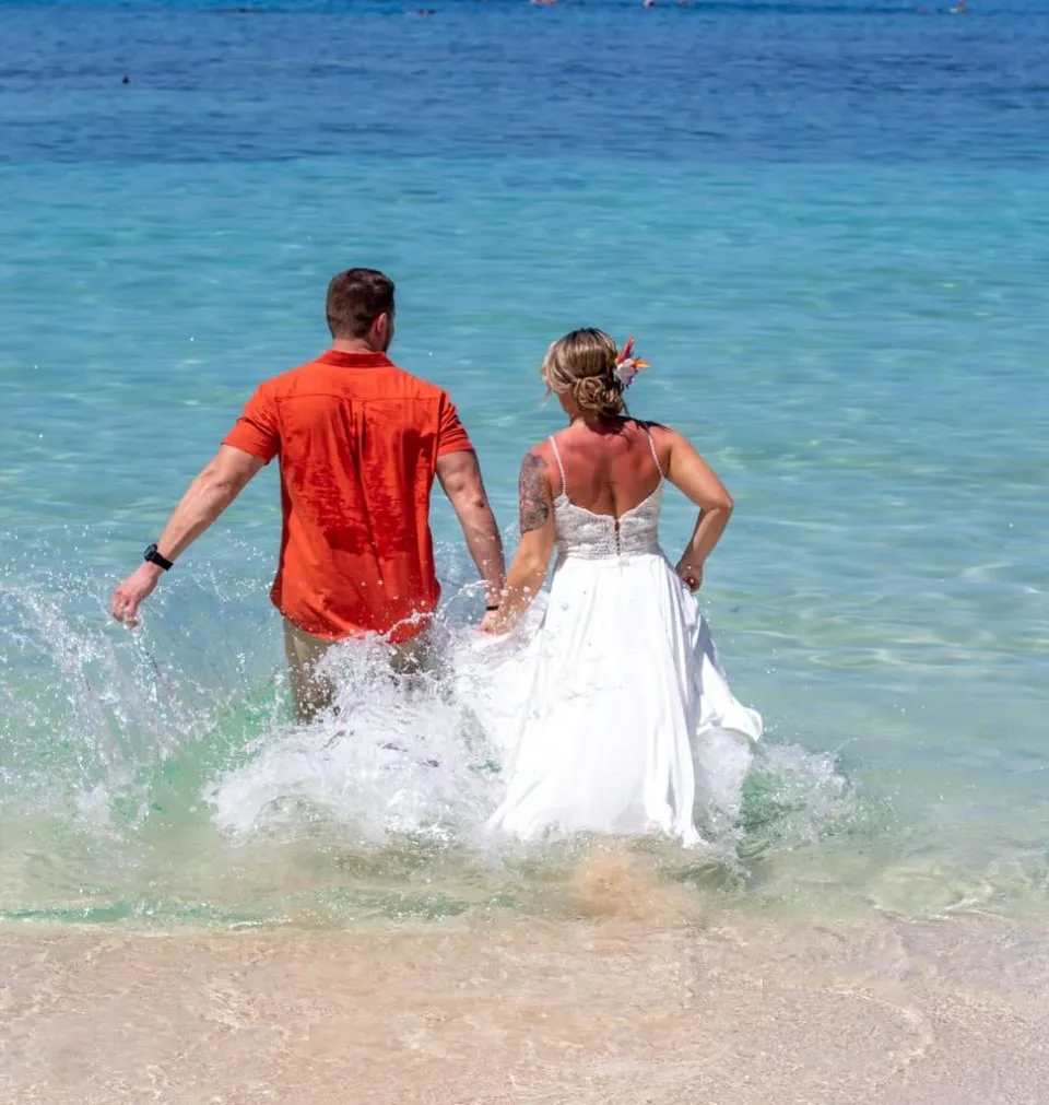 Newlyweds running into the sea after their beach wedding
