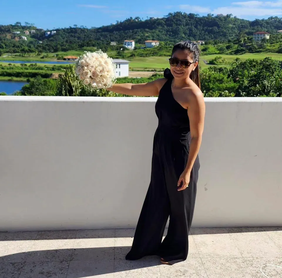 Wedding planner Cecilia Mendez holding a bouquet at an ocean-view terrace in Roatán