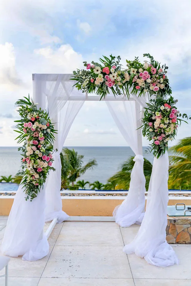 White draped floral wedding arch on a terrace at Pristine Bay, Roatán