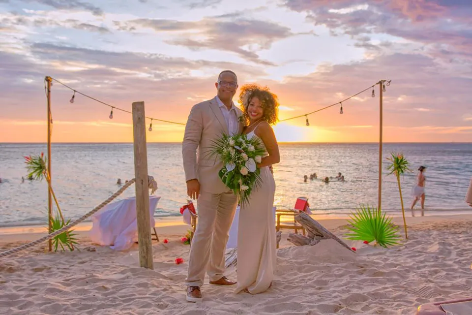 Couple at a beach wedding at sunset under string lights in Roatán