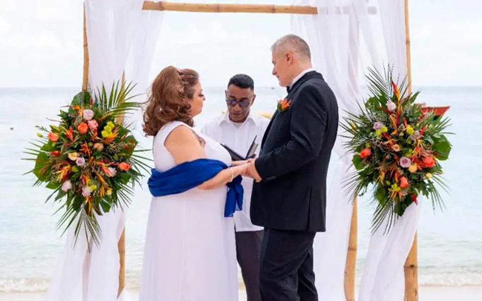 Couple getting married under a tropical flower arch on a Roatán beach during a cruise stop