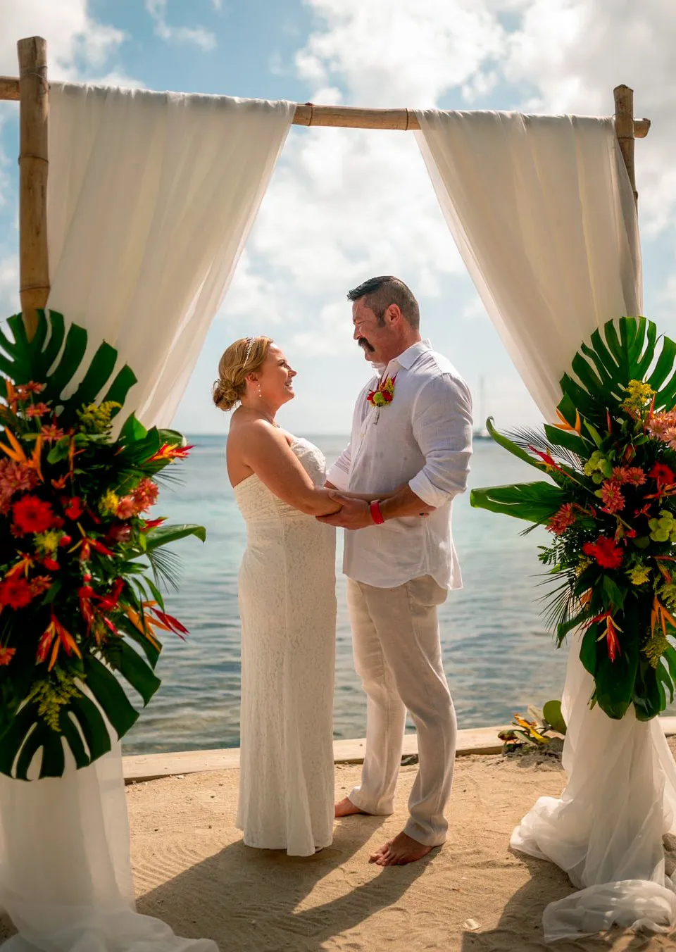 Cruise wedding couple under a tropical floral arch in Roatán