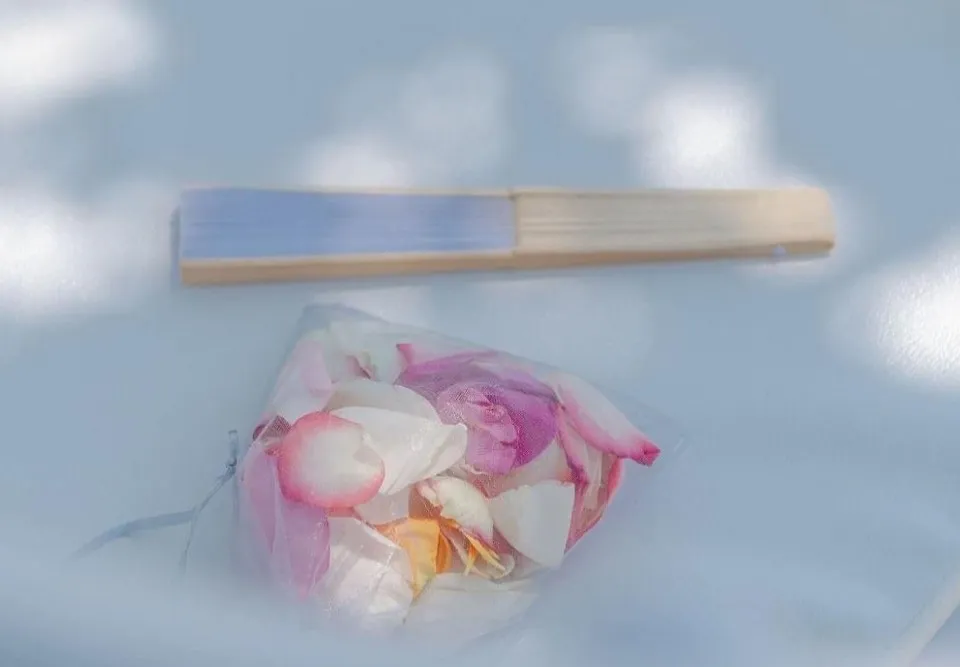 Hand fan and flower petals as personalized wedding favors