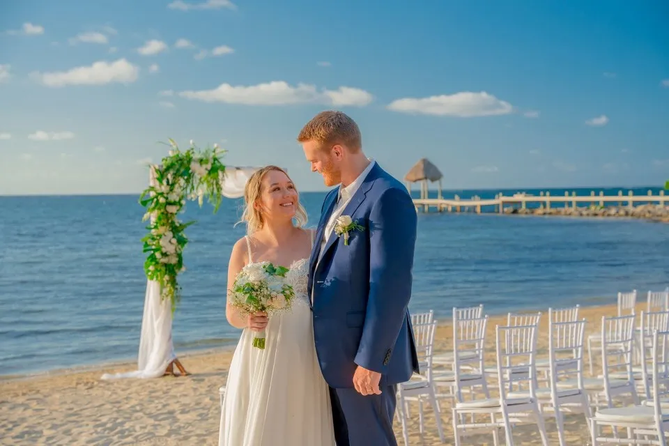 Ben and Natalia posing by the floral arch on the beach at Pristine Bay