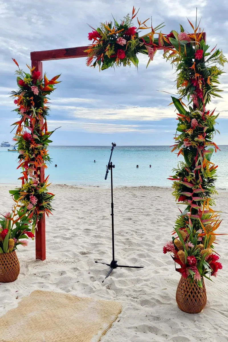 Wedding arch covered in tropical flowers on a Roatán beach