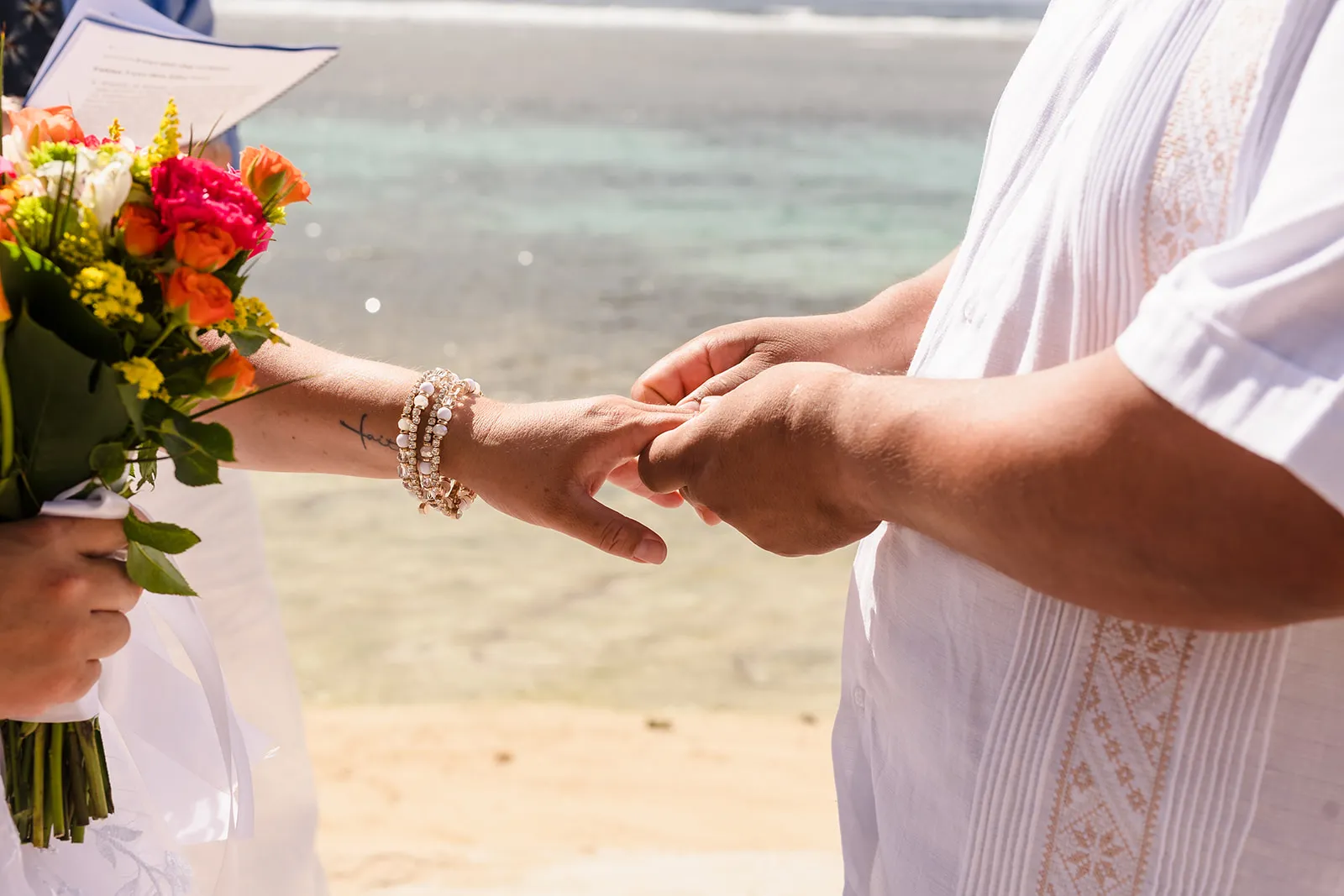 Close-up of Fabian and Elisa holding hands during their beach vows