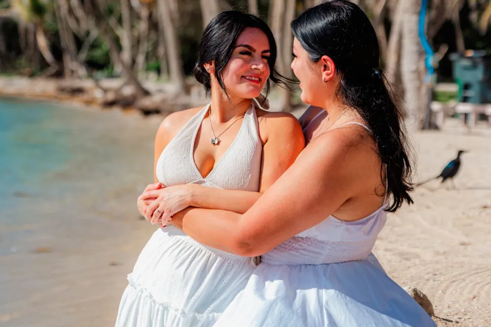 Two women embracing on the beach after a surprise proposal at Curación Beach Resort