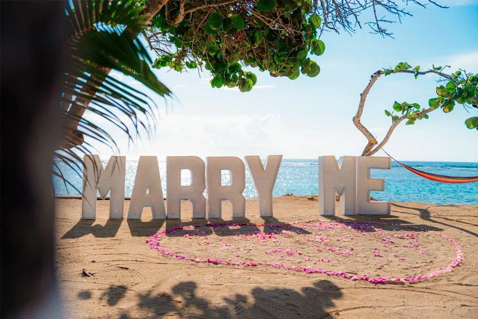 MARRY ME letters and a rose petal heart on a Roatán beach