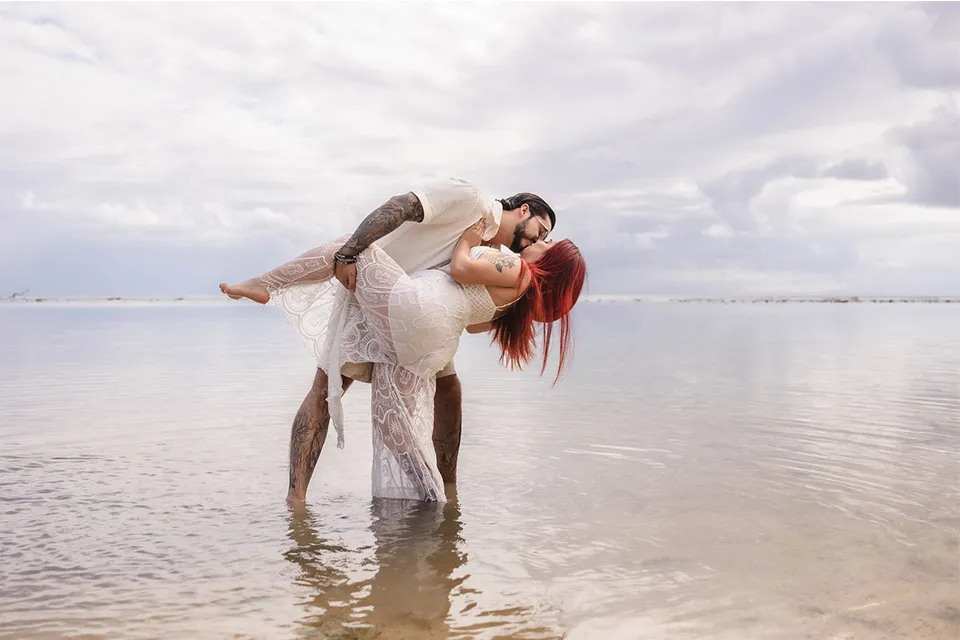 Groom dipping his bride in the shallow water on a Roatán beach