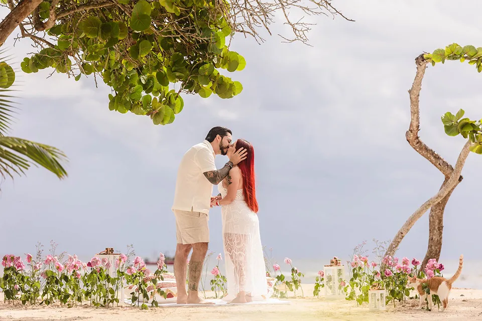 Diego and Regina embracing among flowers after their beach proposal in Roatán
