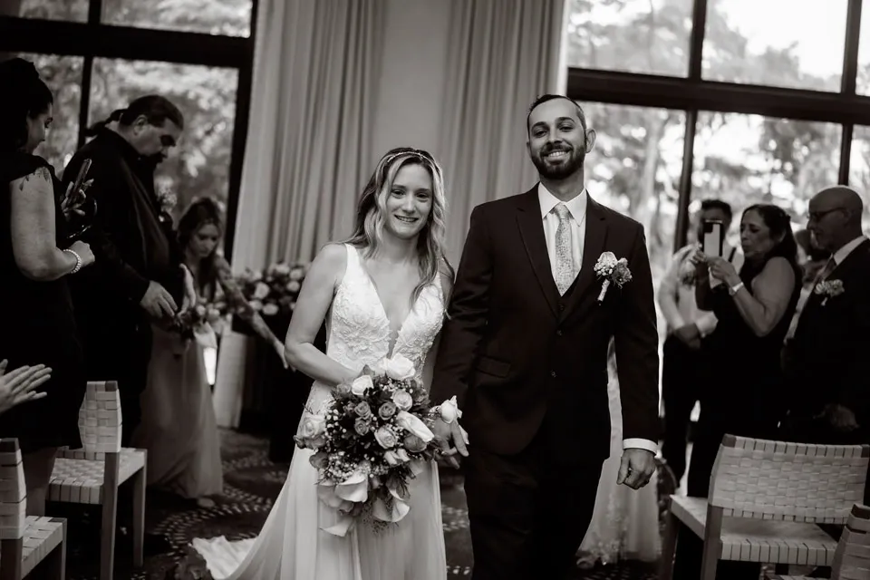 Black and white photo of Audrey and Michael walking up the aisle at Kimpton Grand Roatán