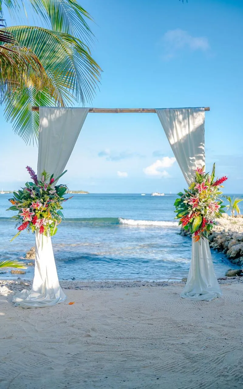 Draped wedding arch with tropical flowers on the beach at Bando Beach, Utila