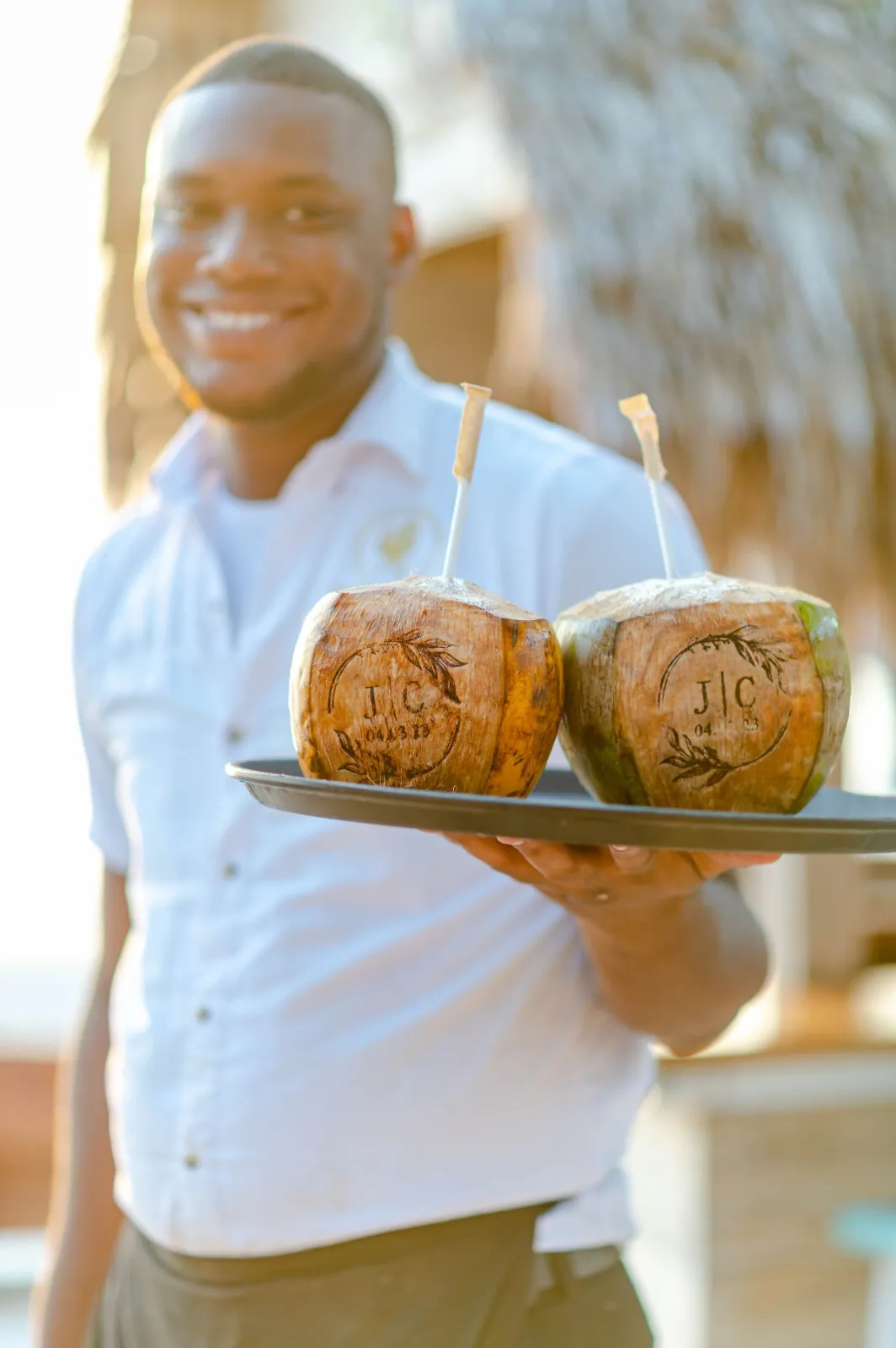 Waiter serving drinks in coconuts at a tropical wedding in Roatán