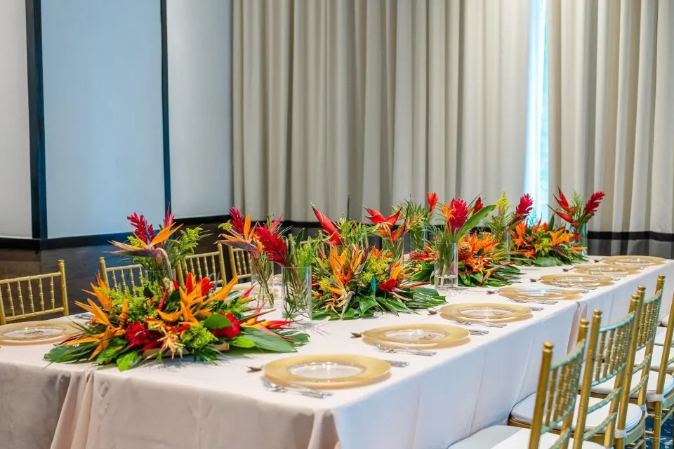 Long reception table with tropical flower runners and gold chargers