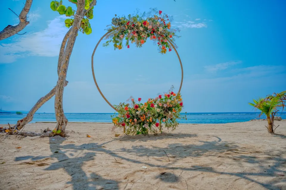 Circular floral arch on the beach at Curación Beach Resort for Tambra and Bob's cruise wedding
