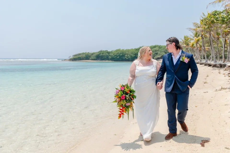 Bride and groom walking on the beach during their cruise wedding day