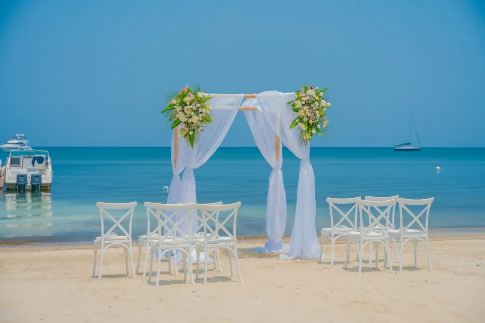 White draped arch and chairs on the beach for a cruise wedding in Roatán