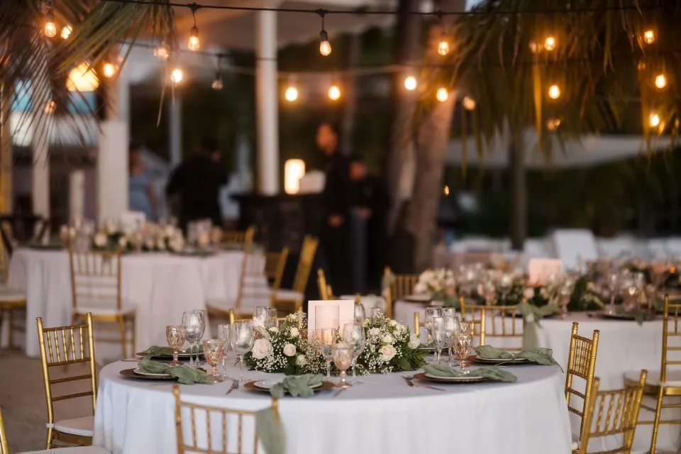 Reception tables with gold chairs and white flowers under string lights