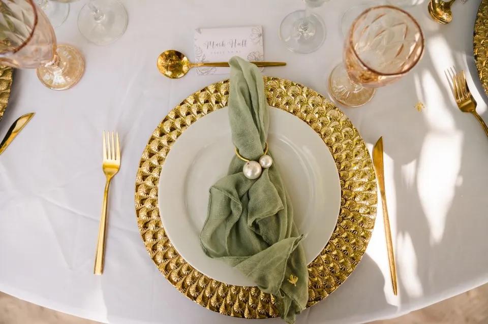 Wedding place setting with gold charger and sage green napkin