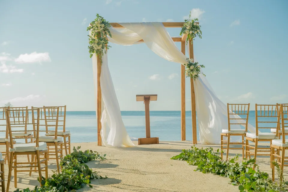 Beach wedding ceremony arch with white draping and flowers overlooking the Caribbean Sea in Roatán